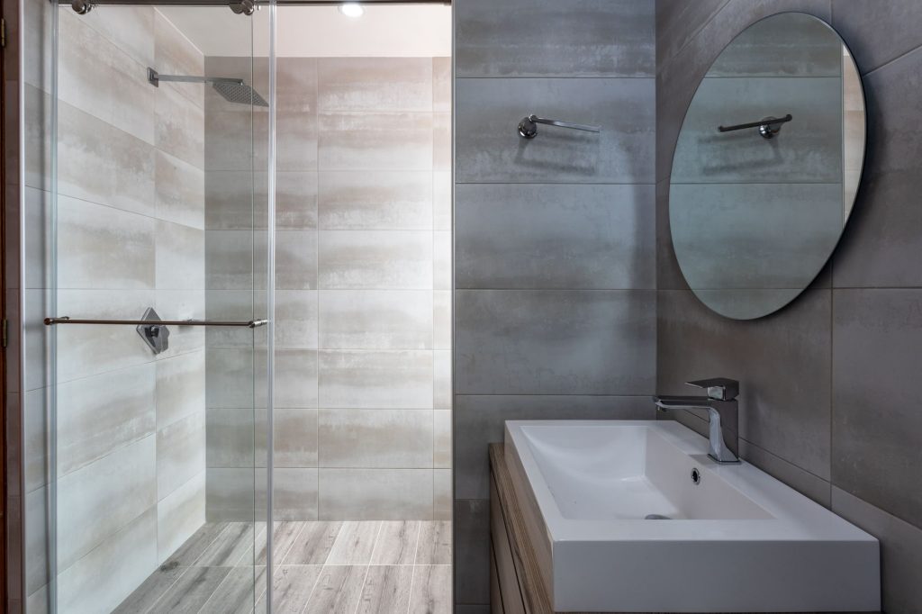 Moderne badkamer met glazen inloopdouche en ronde spiegel